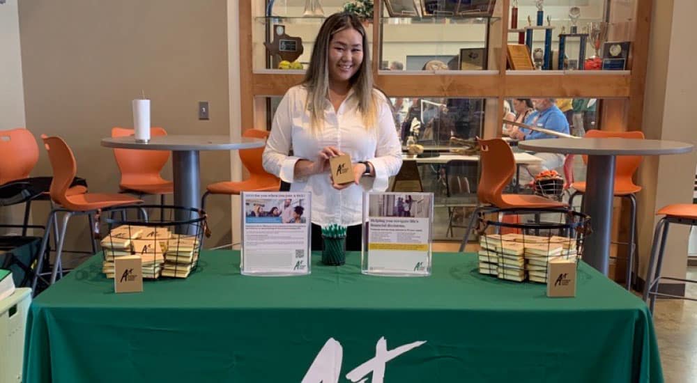 A+ team member poses at A+FCU table at an event.