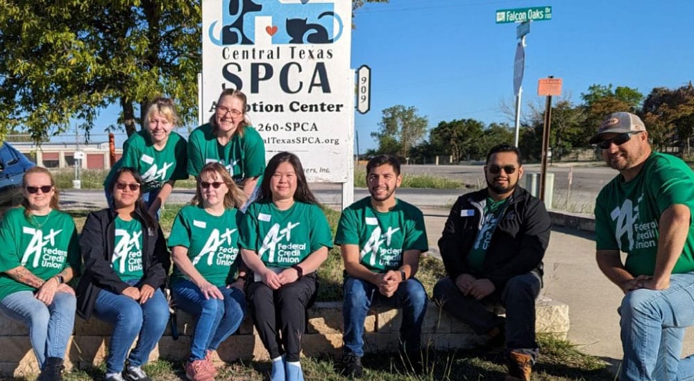 Team A+ poses in front of the Central Texas SPCA sign.