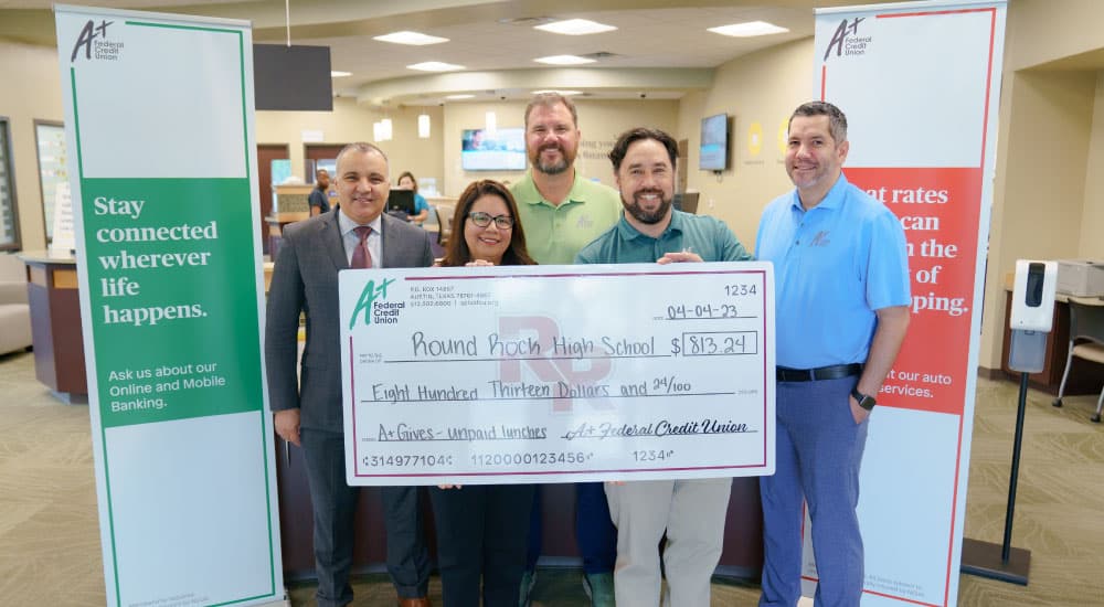 A+ presents a check to Round Rock ISD to pay for unpaid lunch balances