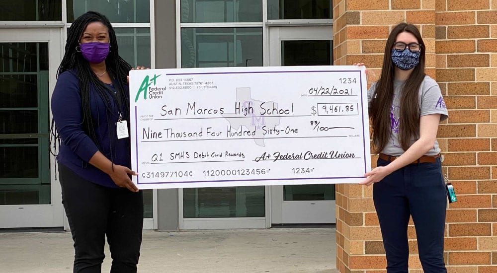 A+ team member presents large check for debit card rewards to San Marcos High School staff member