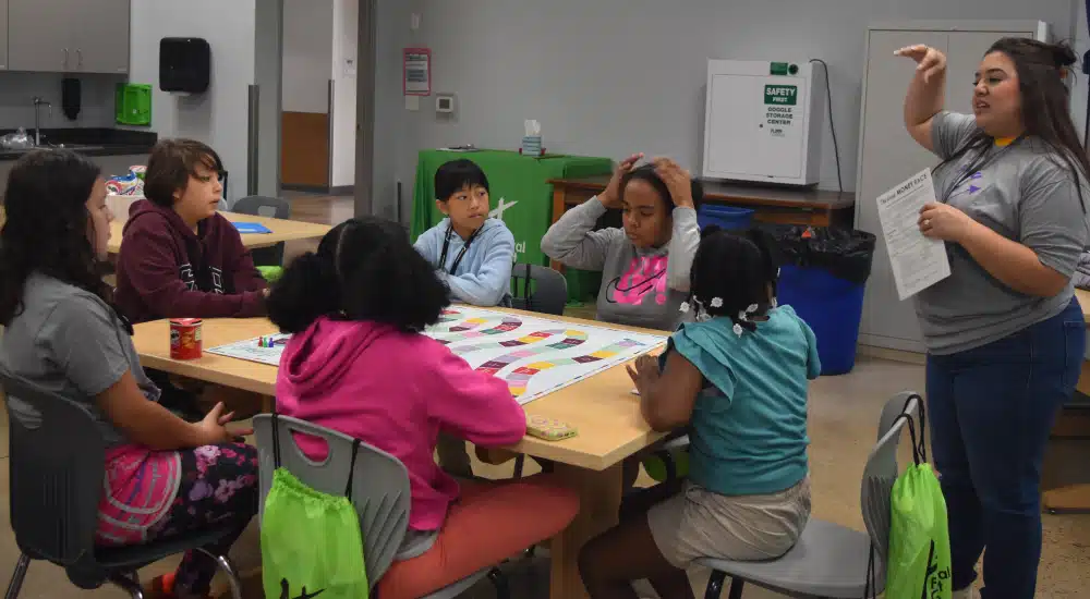 Camp counselor teaches campers how to play a board game.
