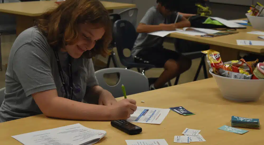 Camper fills out a budget worksheet during a financial simulation.