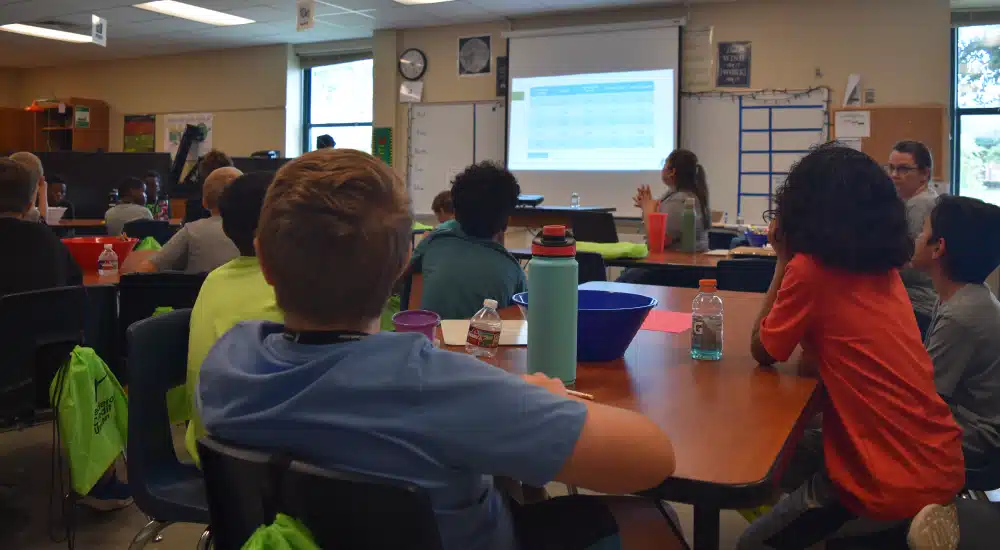 Campers play a game answering questions for camp cash.