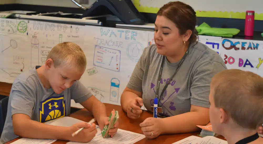 Camper works on his budget worksheet while making decisions during a financial simulation.
