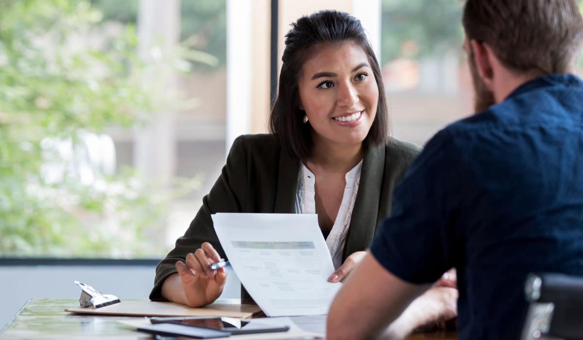 two people looking over a piece of paper with numbers on it, they are smiling at each other.